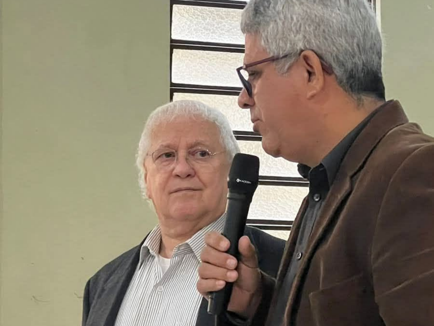 Rev. Gerson ouvindo um pastor que fala ao microfone