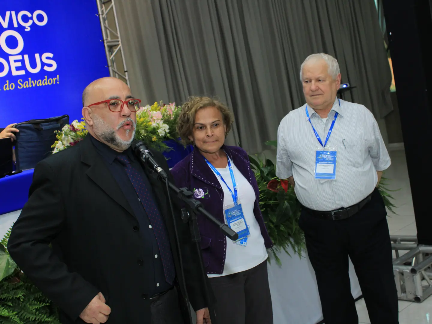 Rev. Gerson ao lado de sua esposa Cleyde e de um pastor ao microfone